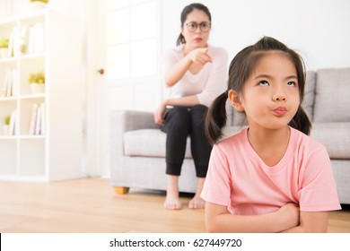 young lovely children was bored with her angry mother loudly nag feeling impatient hate annoying when mom was sitting behind her on sofa in living room at home.