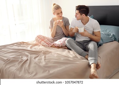 Young lovely couple drinking coffee on bed