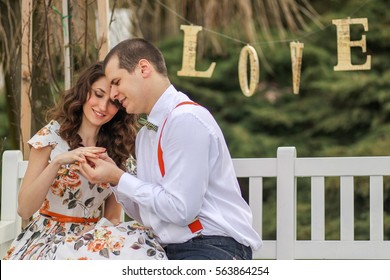 Young Lovely Couple Playing And Laughing Near A Love Sign, Engagement Photo