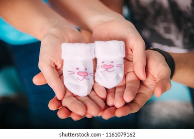 young lovely happy pregnant couple holding a cute baby socks.baby expectation, pregnancy concept. - Powered by Shutterstock