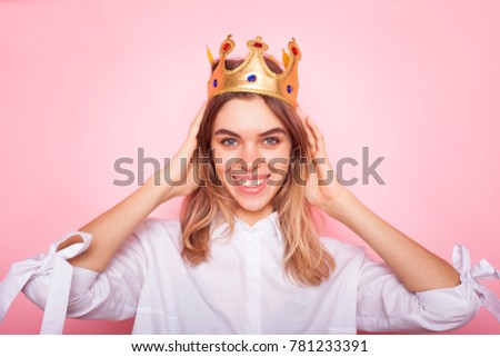 Young lovely woman in crown on pink background 
