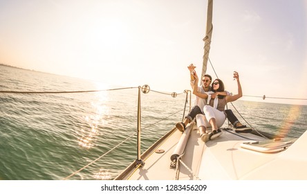 Young Lovers Couple On Sail Boat With Champagne At Sunset - Exclusive Luxury Concept With Rich Millennial People Lifestyle On Tour Around The World - Soft Backlight Focus On Warm Sunshine Filter