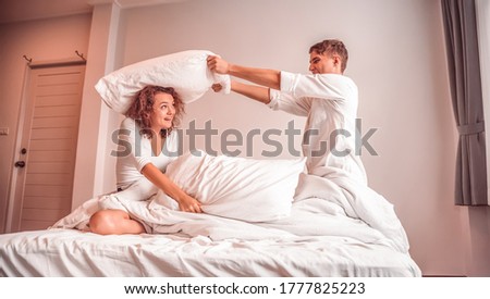 Young lovers in happiness, Couples use a pillow to tease each other on the bed.