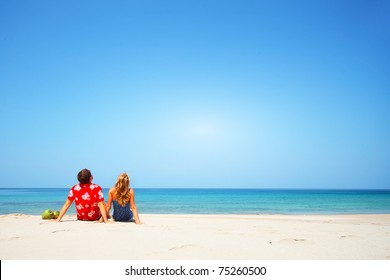 Young lovers sitting on warm sand at sunny day and looking to somewhere - Powered by Shutterstock