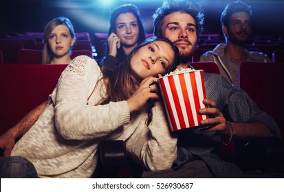 Young Loving Couple At The Cinema Watching A Movie, She Is Eating Her Boyfriend's Popcorn