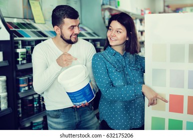 Young loving couple deciding on a best color scheme in a paint supplies store. Focus on both persons - Powered by Shutterstock