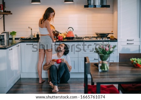 Young loving couple in the morning in the kitchen at home. Man and woman have a fun breakfast in a beautiful stylish kitchen.