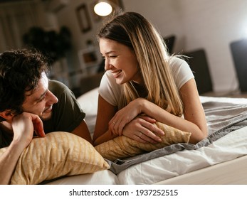 Young loving couple relaxing on bed together. Happy couple watching movie at home.	