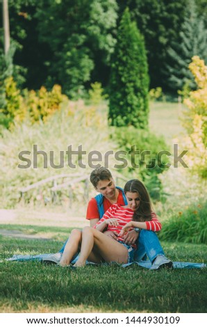 young loving couple is sitting on a plaid in the park, hugging, fooling around and enjoying nature. Picnic for couples in love. Pleasant summer weekends, camping
