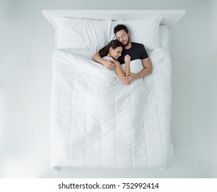 Young Loving Couple Sleeping In Bed, They Are Hugging, Top View