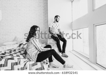 A young loving couple spends time together in their large light bedroom. Black and white photo