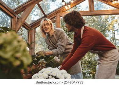 Young loving gay couple are meticulously tending to plants in a charming greenhouse. They share smiles and laughter, highlighting the joy of gardening together amidst lush greenery and bright blooms. - Powered by Shutterstock