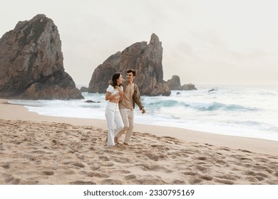 Young loving man embracing his girlfriend, couple walking on nature background, enjoying date and time together on the beach by ocean shore, full length, free space - Powered by Shutterstock