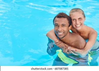 Young Loving Mixed Race Couple - Black Guy And Caucasian Girl Hugging Standing In Swimming Pool During Holiday On Warm Summer Day