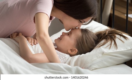 Young Loving Mom Kiss Smiling Little Daughter In Forehead Wish Her Sweet Dreams And Good Night, Caring Mother Put Small Preschooler Girl Child To Bed, Caress Cuddle Her Before Day Nap Time