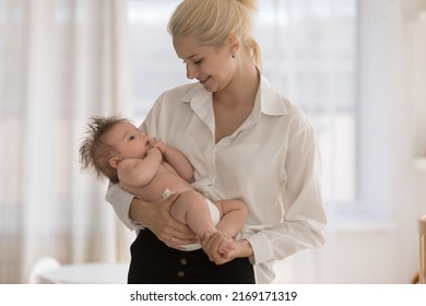 Young loving mom standing in cozy nursery carrying, lulls, calms her adorable 0-6 baby in diaper, enjoy time together, relish moments of tenderness feeling love. Being mother, happy motherhood concept - Shutterstock ID 2169171319