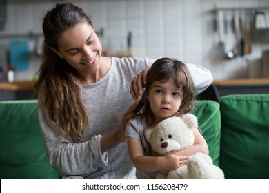 Young loving mother brushing kid daughters hair sitting on sofa, smiling single mom sister helping child girl with hairstyle at home getting ready, family care, morning preparations lifestyle concept - Powered by Shutterstock