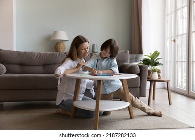 Young loving mother   preschooler son drawing and colored pencils in paper sketchbook  enjoy weekend  communication  hobby together  Art class at home  children development  family pastime
