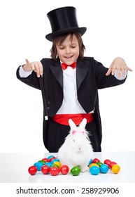 Young magician boy performing an easter trick - conjuring a white rabbit with colorful eggs, isolated - Shutterstock ID 258929906