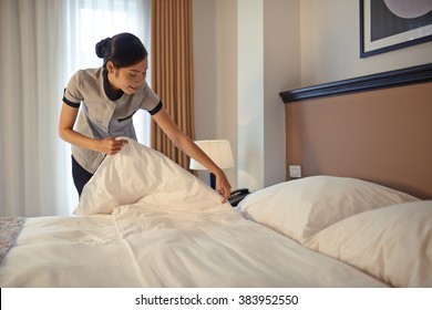 Young maid arranging blanket on bed in hotel room - Shutterstock ID 383952550