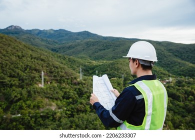 Young maintenance engineer man  working with blueprint on the mountain, Environmental engineering concept. - Shutterstock ID 2206233307