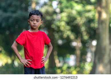 Young Malay Boy In A Red Shirt Posed At A Park.