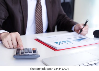 Young Male Accountant Or Banker Using Calculator Calculating Business Report Document In Office.