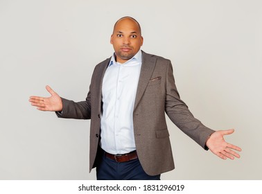 Young male African American businessman looking at the camera, spread his hands guiltily. An ignorant and confused expression with raised arms and hands. Doubt concept