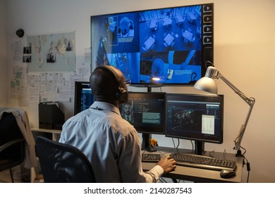 Young Male Agent Of Secret Service In Headphones Watching Record Of Crime In Hotel Lounge While Sitting In Front Of Large Screen