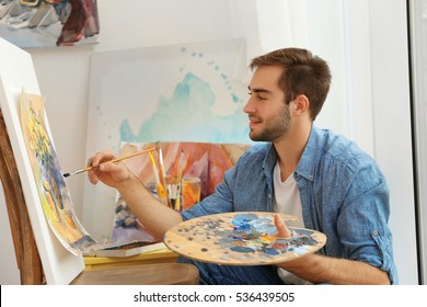 Young Male Artist Painting Picture In Studio