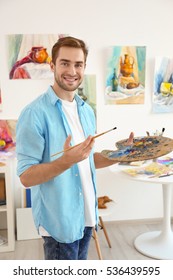 Young Male Artist With Palette And Brush In Studio