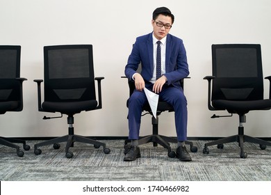 Young Male Asian Job Seeker Sitting In Chair Appears To Be Frustrated And Defeated