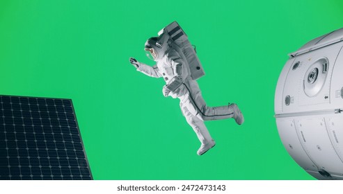 Young Male Astronaut Floating in a Space Suit on an Isolated Green Screen Background Together with a Mock Up Spaceship, Satellite or a Space Station with Modern Solar Panels - Powered by Shutterstock