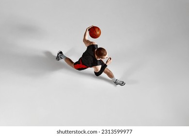 Young male athlete, concentrated basketball player in motion during game against grey studio background. Aerial view. Concept of professional sport, hobby, healthy lifestyle, action and motion - Powered by Shutterstock