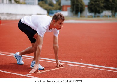 Young male athlete in starting position on a running track. - Powered by Shutterstock