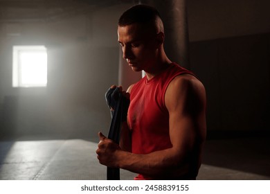 Young male athlete wrapping his punch with blue flexible band before boxing training or competition to protect his hand from injury - Powered by Shutterstock