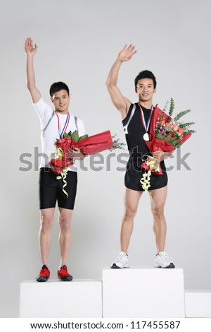 Young male athletes holding trophy and flowers