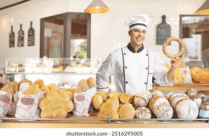 Young male baker holding a simit in a bakery shop - Powered by Shutterstock