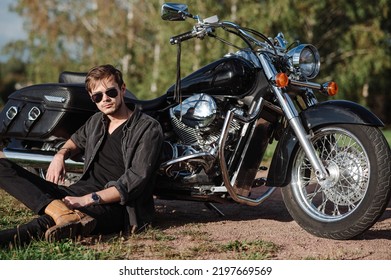 Young Male Biker Sitting On The Ground With His Motor Bike