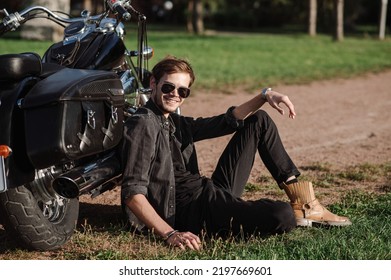 Young Male Biker Sitting On The Ground With His Motor Bike