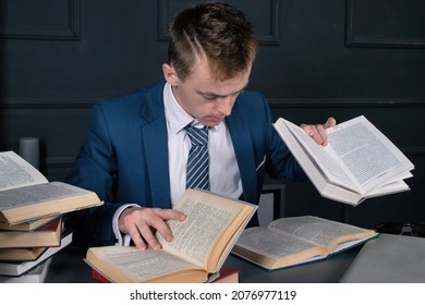 Young male businessman is sitting in the office reading books and encyclopedias. The student is preparing for exams.
