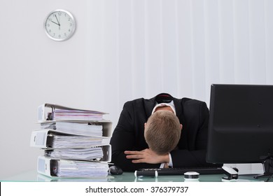 Young Male Businessman Sleeping On Desk In Office
