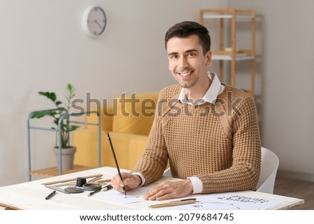 Young male calligrapher working in office