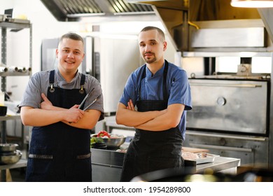 A Young Male Caucasian Chef In The Kitchen Of The Restaurant. Cooking.