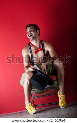 Young male circus performer seated backstage in front of red wall