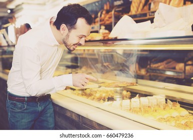Young male client choosing delicious dessert in bakery