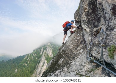 Young male climber climbing Via ferrata Astragalus, Romania, Europe in summer. Changing carabiners on cable. - Powered by Shutterstock