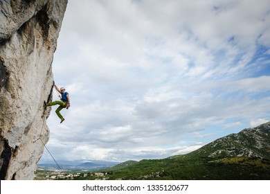 Young Male Climber Hanging By A Cliff