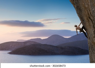 Young male climber hanging by a cliff 