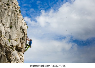 Young Male Climber Hanging By A Cliff